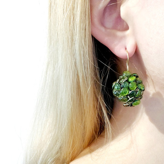 Round Green Resin Earrings. Droplets of green resin and sterling silver are sewn in with purple thread. These earrings measure 2.2cm in diameter, and hang from sterling silver hooks.