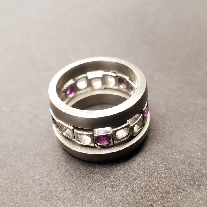 Geometrica stacking ring set with 5 purple sapphires interspaced across the staggered cubes of the sterling silver band, best worn between the 2 titanium bands.