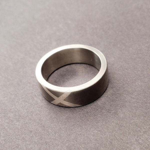 A sweeping fine silver "X" marks the spot, impeccably inlaid on the 7 mm titanium band. Size 9.