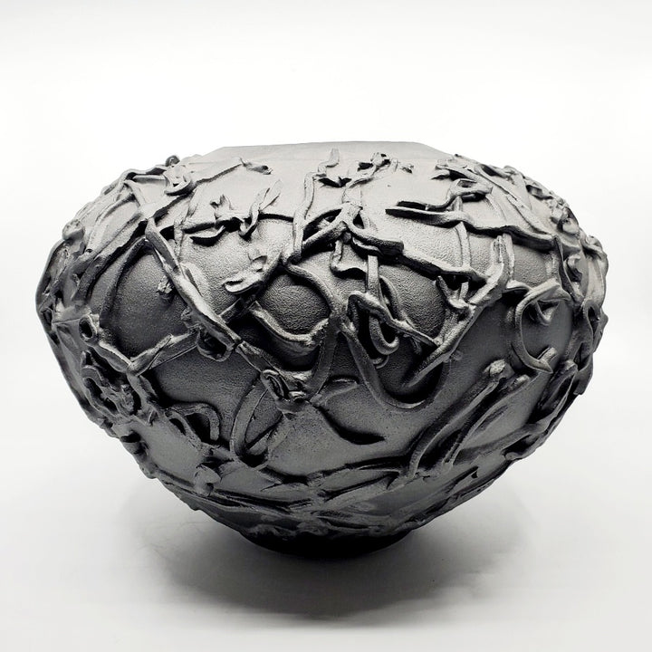 Large black vase. Ribbons of clay applied to its surface create a strong texture.