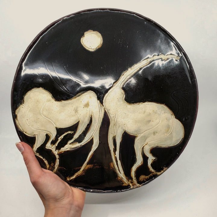 Ceramic plate depicting two horses. 12" in diameter.