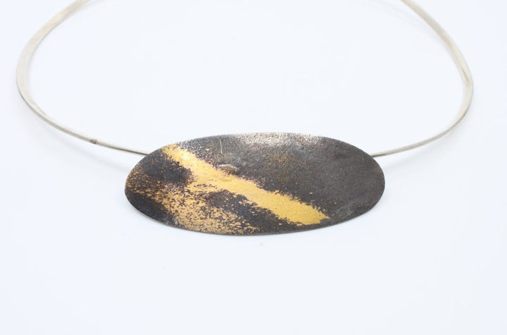 Aggie Beynon Pendant is composed of silver, pure gold and copper. The oval pendant is situated on a sterling silver collar.
