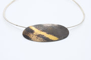 Aggie Beynon Pendant is composed of silver, pure gold and copper. The oval pendant is situated on a sterling silver collar.