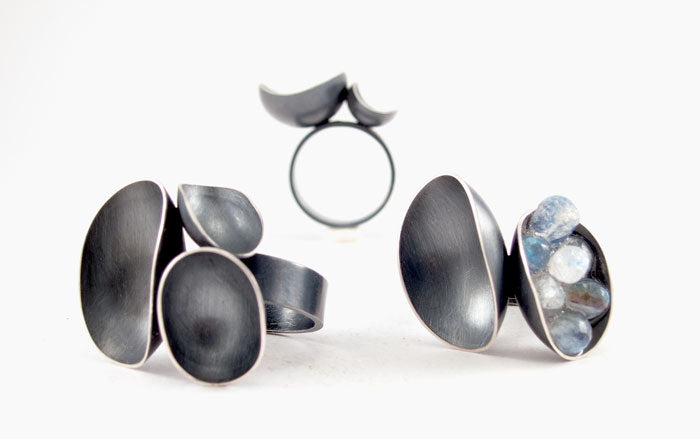 Wax and Wane Rings, of oxidized sterling silver, 3 x 2.5 x 1.5 cm high from the finger.  Three Bowls, in sizes 8 and 9, $360; Two bowls, one filled with faceted moonstone beads, 6.75, $410.