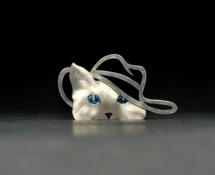 Claudine. Sterling silver cat with sparkling blue cubic zirconia eyes and cut-out cowboy hat. This pin has two locking pin backs.