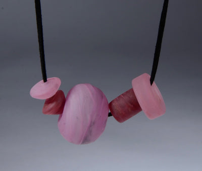 Asymmetric Beaded Necklace. Necklace of blown glass and solid glass beads in pink, on an adjustable length suede leather cord.