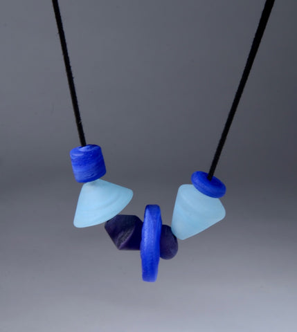 Asymmetric Beaded Necklace. Necklace of blown glass and solid glass beads in blue, on an adjustable length suede leather cord.