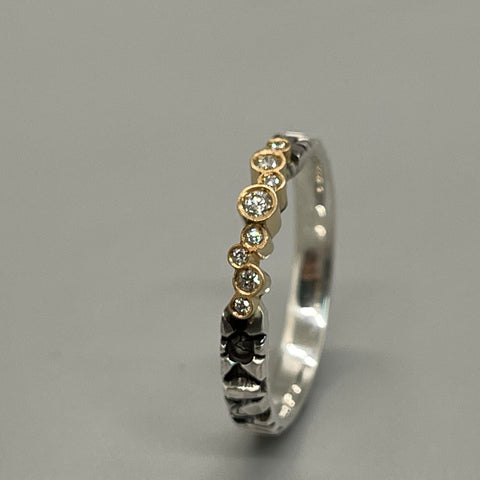 Elegant stamped sterling silver ring with an asymmetrical line of 8 diamonds and 18k gold. 3mm band.