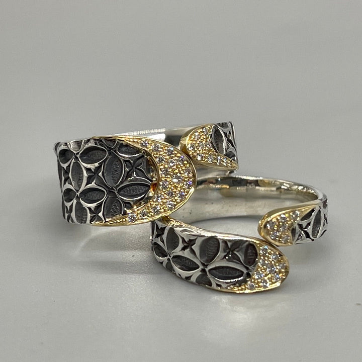 Stamped sterling silver ring. Two rounded ends meet in the middle, each capped with diamonds and 18k gold. (Bottom ring in image.)
