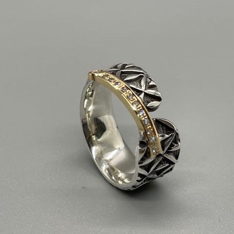 Stamped sterling silver ring. A diagonal band of diamond and 18kt yellow gold joins two rounded ends. The line is capped by a single larger diamond.
