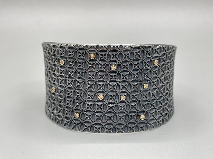 Sterling silver cuff, stamped with a geometric pattern, and dotted with 10 small diamonds set in 18k gold.