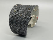 Sterling silver cuff, stamped with a geometric pattern, and dotted with 10 small diamonds set in 18k gold.