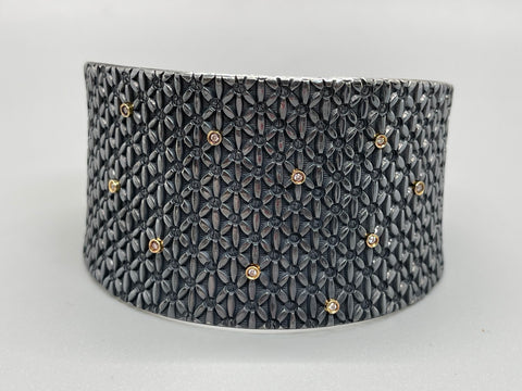 Sterling silver cuff, stamped with a geometric stamped floral pattern, and dotted with 10 small diamonds set in 18k gold.