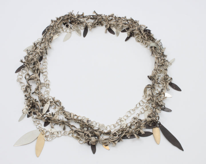 A long linen thread neckpiece with small black leaves doubles the sterling silver link chain with silver and brass leaves. Wear together to experience the textural contrast or singly to enjoy the fineness of each. 42"/106 cm.
