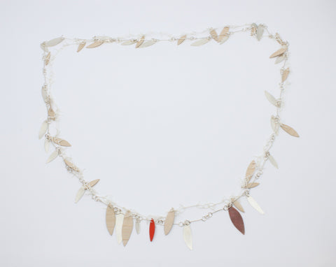 A long, loosely-knotted  white linen thread neckpiece with birch plywood leaves, one painted orange is married to a sterling silver link chain with silver leaves--and one red copper leaf. Delicately balanced together, they can be worn singly. 42"/106 cm.