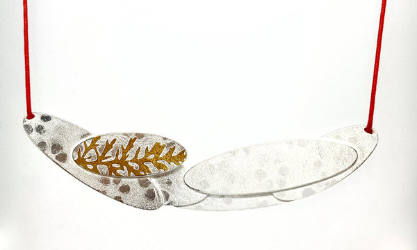 This Fougère keum-boo necklace is sterling silver with 24 karat gold that has been diffusion bonded and formed, resulting in an exciting interplay between two fine metals. On a 20" red cord.