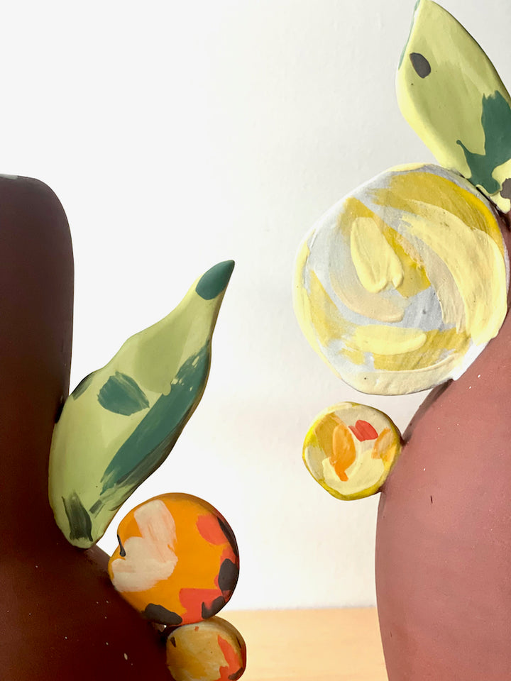 Tall ceramic vessel featuring colourful floral forms. (Pictured on the right)