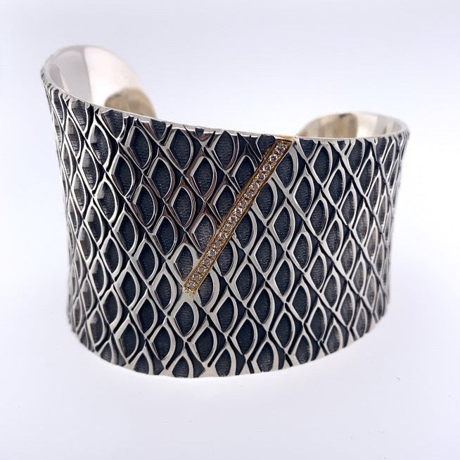Sterling silver cuff adorned with a 18k gold bar motif with diamonds