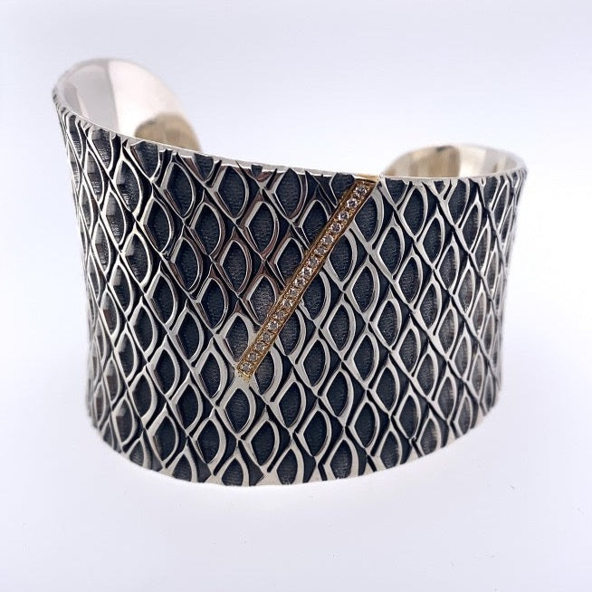 Sterling silver cuff adorned with a 18k gold bar motif with diamonds