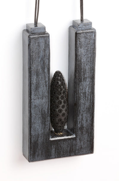 Suspension - necklace made from polyurethane, wood, polymer, powder coated, paint, fibre. Pendant measures 7 cm wide x 14 cm high x 2.3 cm 
