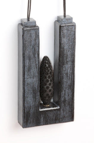 Suspension - necklace made from polyurethane, wood, polymer, powder coated, paint, fibre. Pendant measures 7 cm wide x 14 cm high x 2.3 cm 