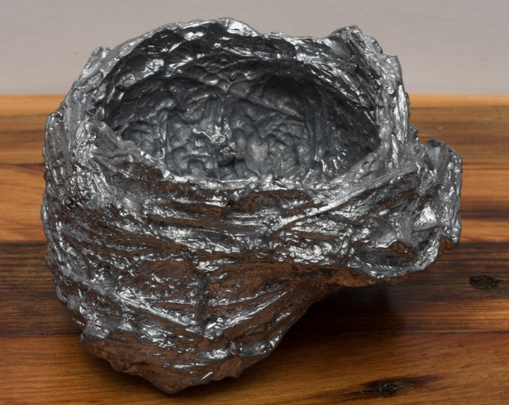 Leaden, ﻿a nest cast in lead on a free-floating lath shelf.  Series of 10 nests, each sold separately.  "A year in paces, a morning ritual of walking has led me to collect numerous bird nests from the thickets along Ottawa’s waterways. In this piece, I have cast each nest in lead salvaged from the torn out ironwork of Parliament Hill— an act of preservation at the perceived fragility of a tiny sanctuary and an exploration of the weighted concept of home and domesticity."
