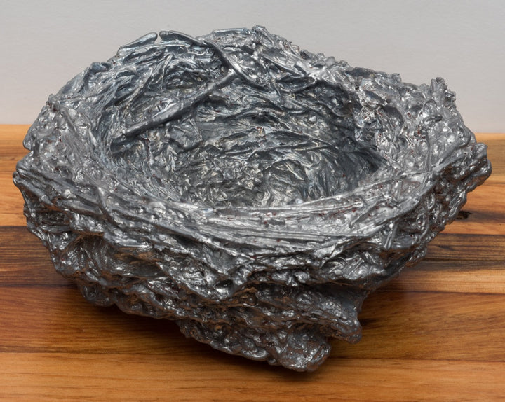 Leaden, ﻿a nest cast in lead on a free-floating lath shelf.  Series of 10 nests, each sold separately.  "A year in paces, a morning ritual of walking has led me to collect numerous bird nests from the thickets along Ottawa’s waterways. In this piece, I have cast each nest in lead salvaged from the torn out ironwork of Parliament Hill— an act of preservation at the perceived fragility of a tiny sanctuary and an exploration of the weighted concept of home and domesticity."