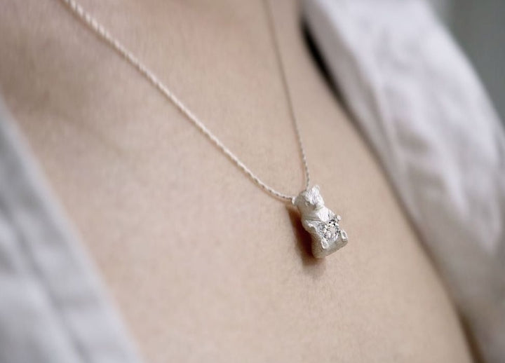 Heart Hugger. Bear pendant necklace of sterling silver, with a heart-shaped Swarovski cubic zirconia crystal. This mini bear is 1.2 cm high.