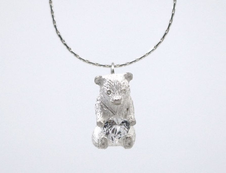 Heart Hugger. Bear pendant necklace of sterling silver, with a heart-shaped Swarovski cubic zirconia crystal. This mini bear is 1.2 cm high.