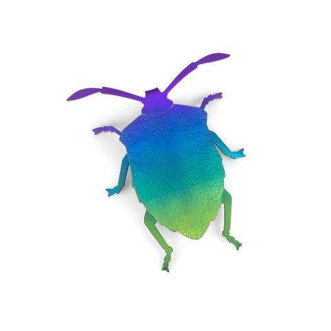 Stink Bug Brooch. Colourful niobium brooch in green, blue, and purple. The underside is also coloured. The pin is made with stainless steel and rubber.