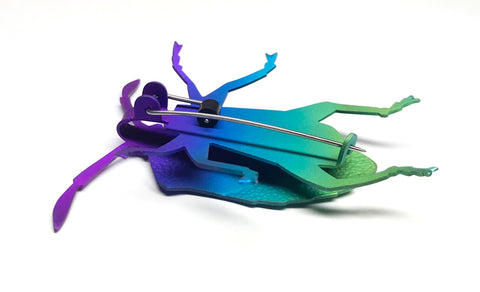 Stink Bug Brooch. Colourful niobium brooch in green, blue, and purple. The underside is also coloured. The pin is made with stainless steel and rubber.